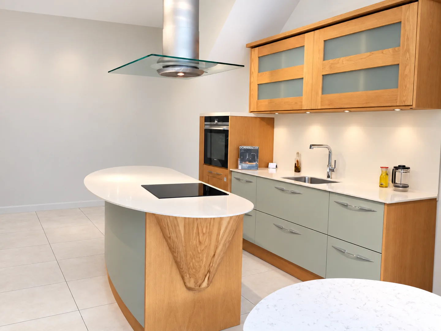 Pale stone kitchen worktop and curved island with timber and grey cabinetry
