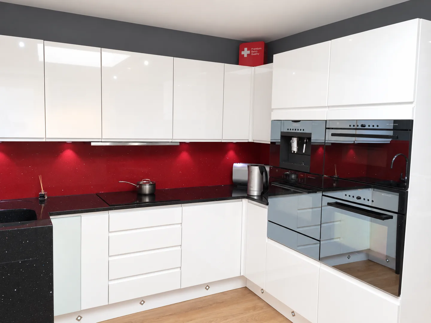 Dark stone kitchen worktop with a red splashback and white cabinets