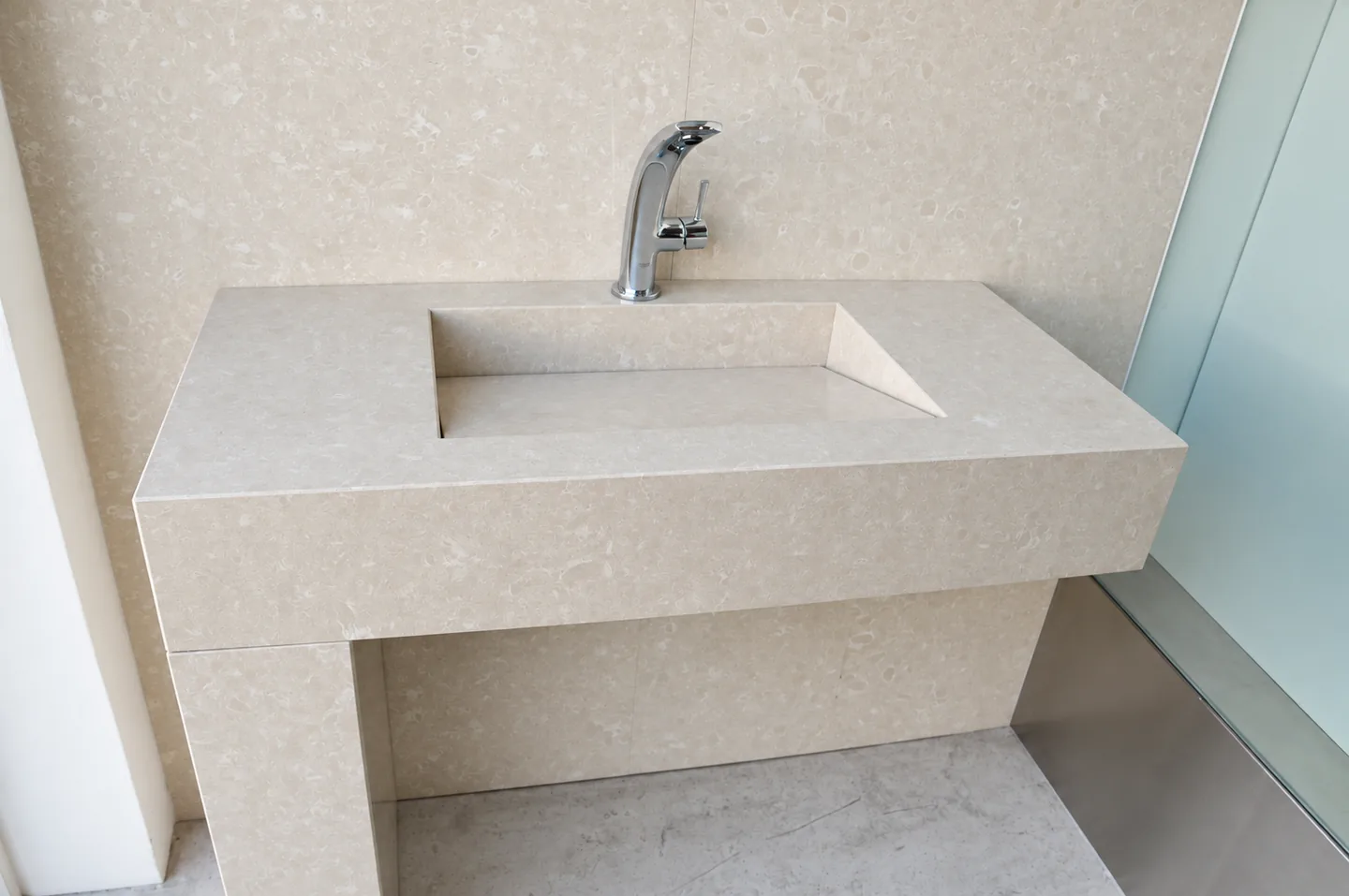 Pale stone basin with a broad rim and matching wall panel