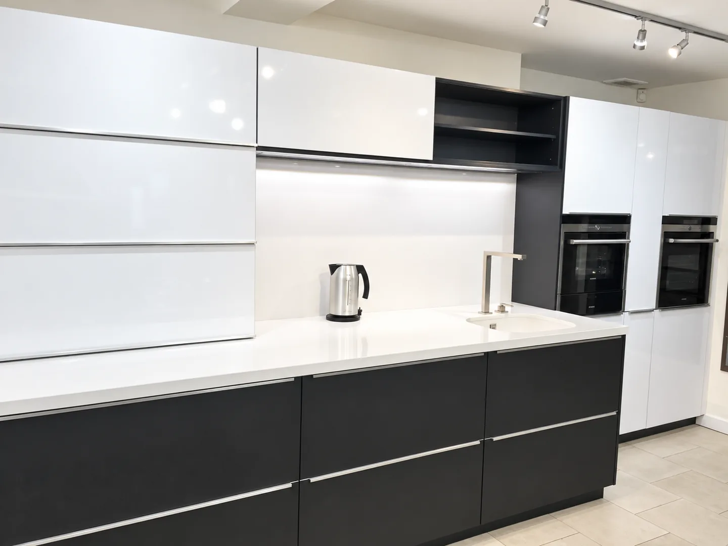 White stone worktop and sink with dark base units and white wall cabinets